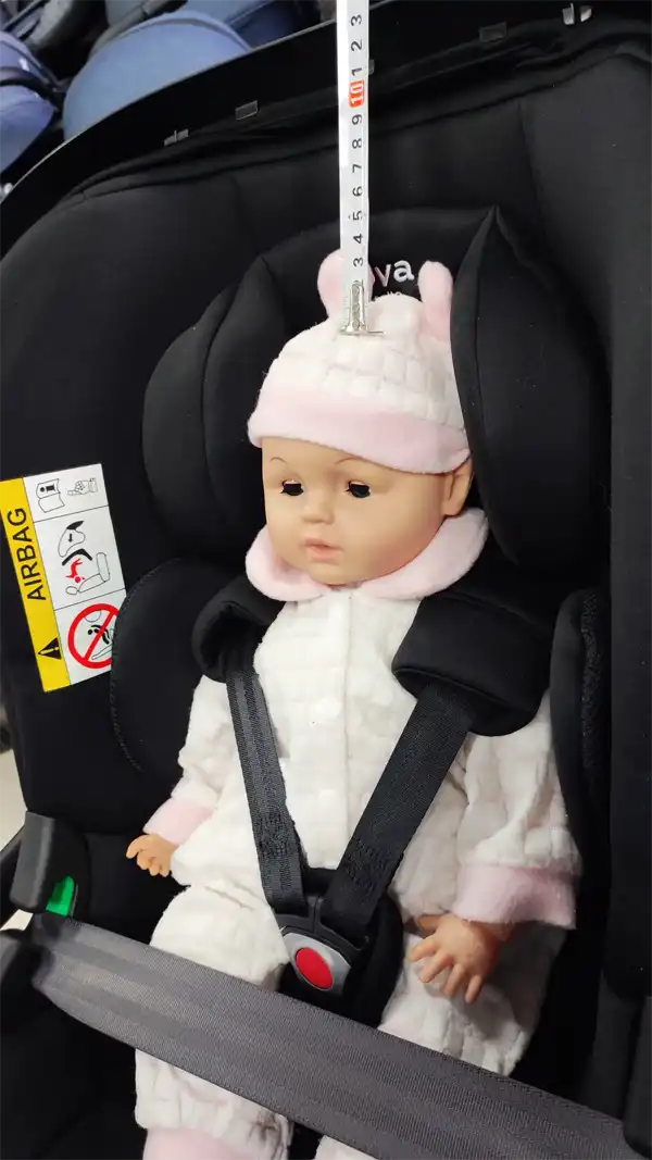 Engineer using a measuring tape to check the 1-inch safety rule on an infant car seat