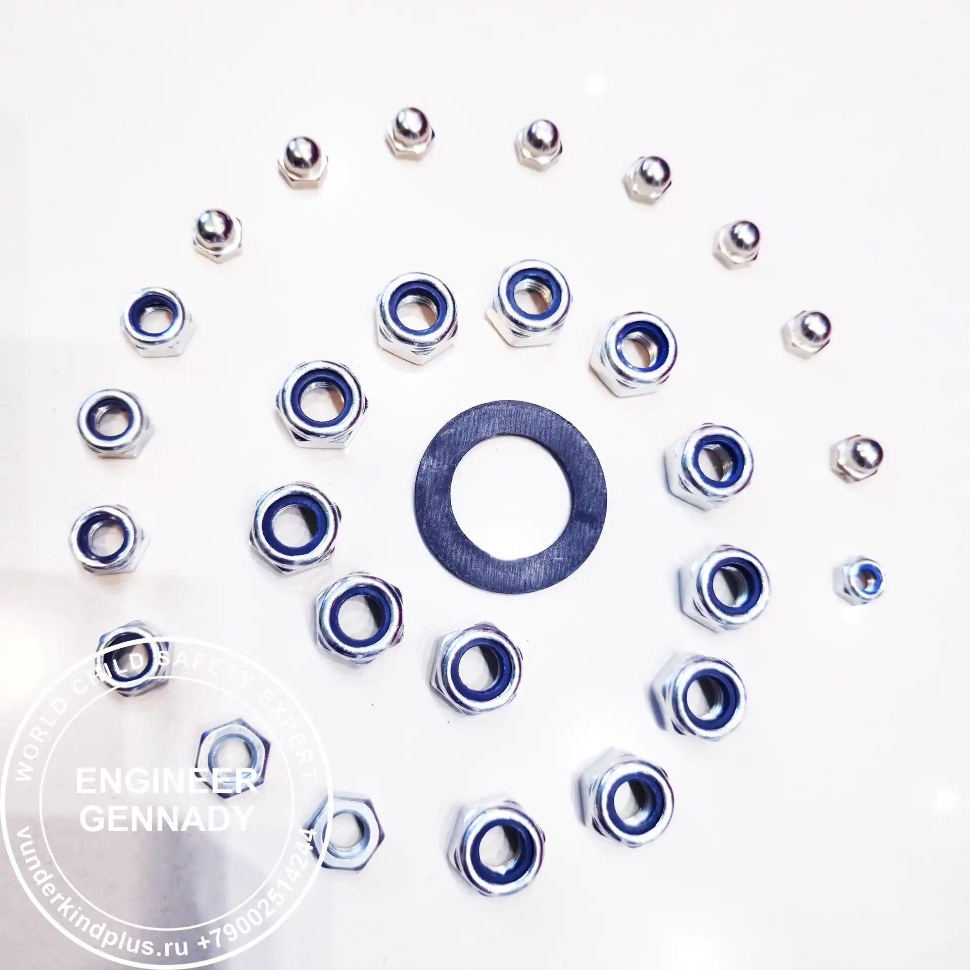 M-Theory of Child Safety. Metal nuts arranged in a spiral galaxy shape with a black washer in the center.