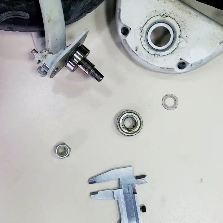 Disassembled front wheel hub of a 3-wheel stroller showing a defective bearing